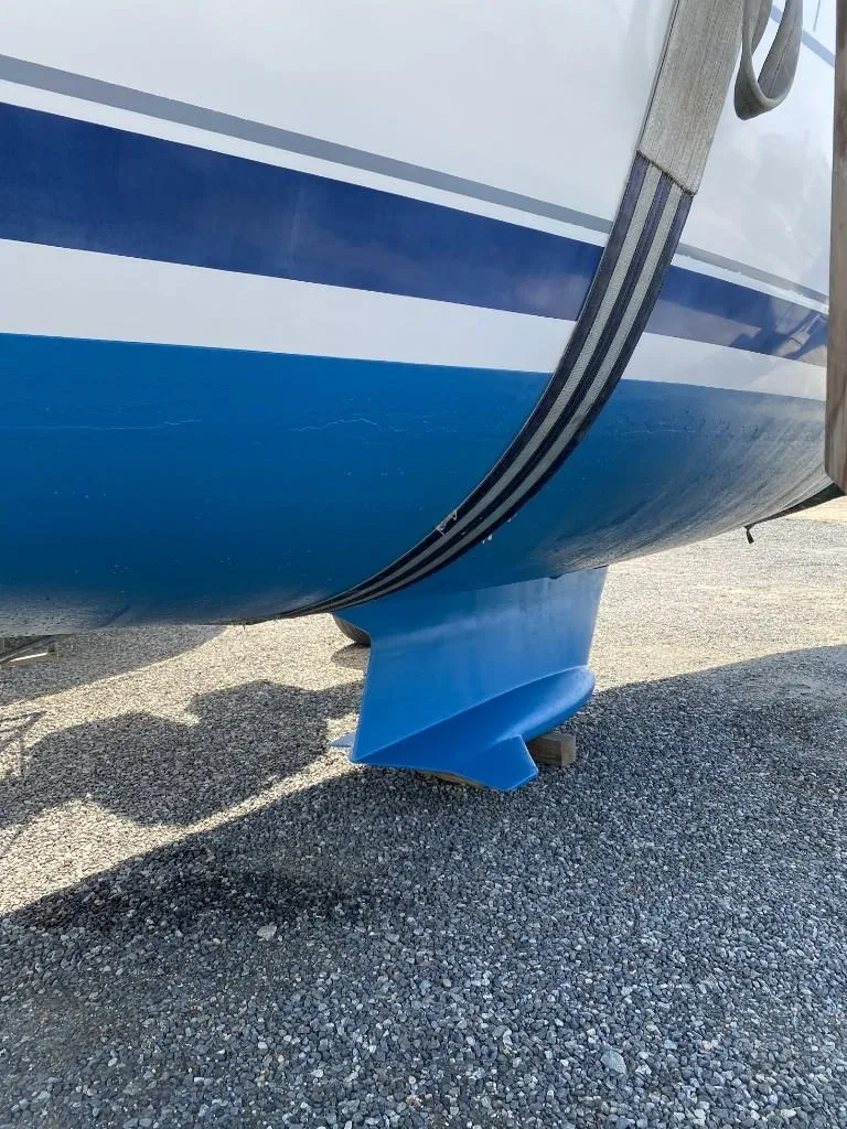 Slide: The Image of Hunter 410 sailboat keel, 2001 model, with blue and white hull on gravel surface. - 9