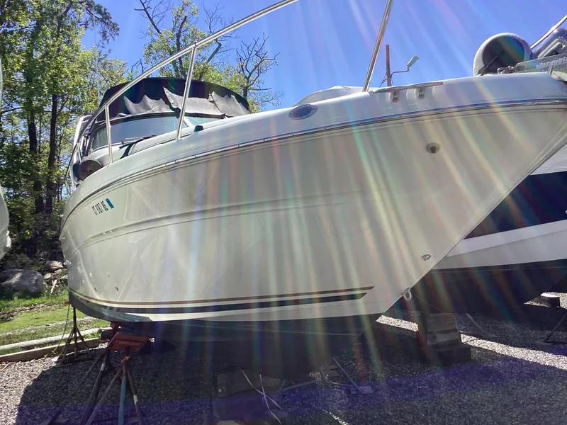 Slide: The Image of 2000 Sea Ray 270 Sundancer boat on stands, sunlit with trees in the background. - 3