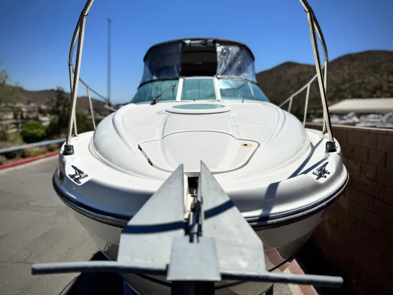 Slide: The Image of 2004 Maxum 2500 SE boat, front view, parked outdoors under clear blue sky. - 10