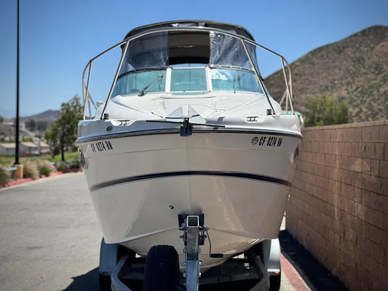 Slide: The Image of 2004 Maxum 2500 SE boat on trailer, parked outdoors near a brick wall. - 2