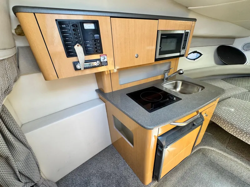 Slide: The Image of 2004 Maxum 2500 SE boat interior with kitchenette, featuring stove, microwave, and sink. - 32