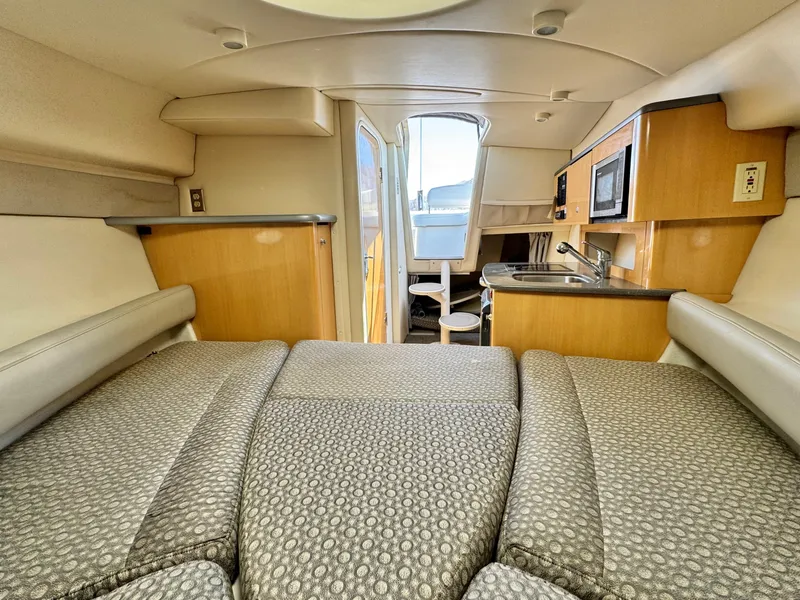Slide: The Image of 2004 Maxum 2500 SE cabin interior with bed, kitchenette, and seating area. - 34