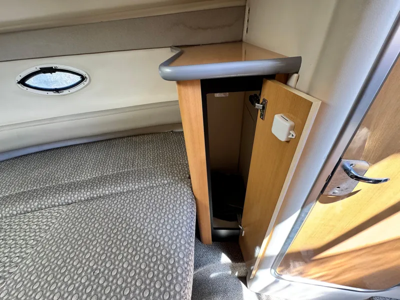 Slide: The Image of 2004 Maxum 2500 SE cabin interior with open storage compartment and cushioned seating. - 36