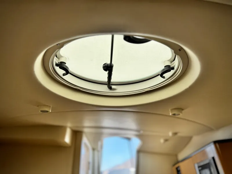 Slide: The Image of Circular hatch inside 2004 Maxum 2500 SE boat, providing natural light and ventilation. - 39