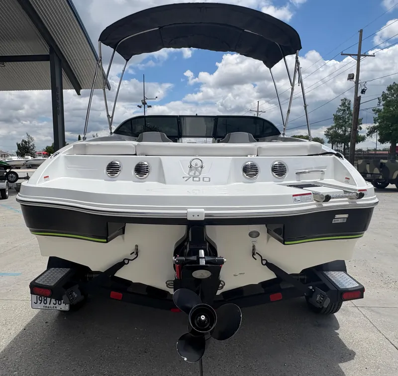 Slide: The Image of 2019 Tahoe 700 boat with canopy, rear view, parked outdoors under cloudy sky. - 4