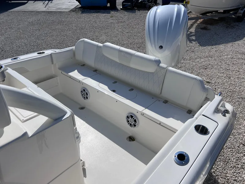 Slide: The Image of 2025 Key West 239FSR boat interior with seating, speakers, and motor, on gravel surface. - 35
