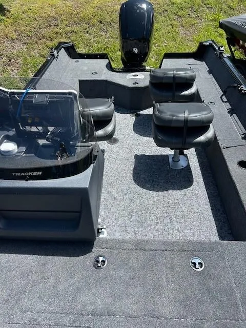 Slide: The Image of 2025 Tracker Pro Guide V-16 SC boat interior with seating and motor, on grassy background. - 6