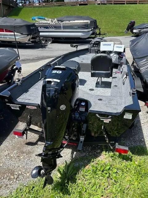Slide: The Image of 2025 Tracker Pro Guide V-16 SC boat with outboard motor, parked outdoors. - 8