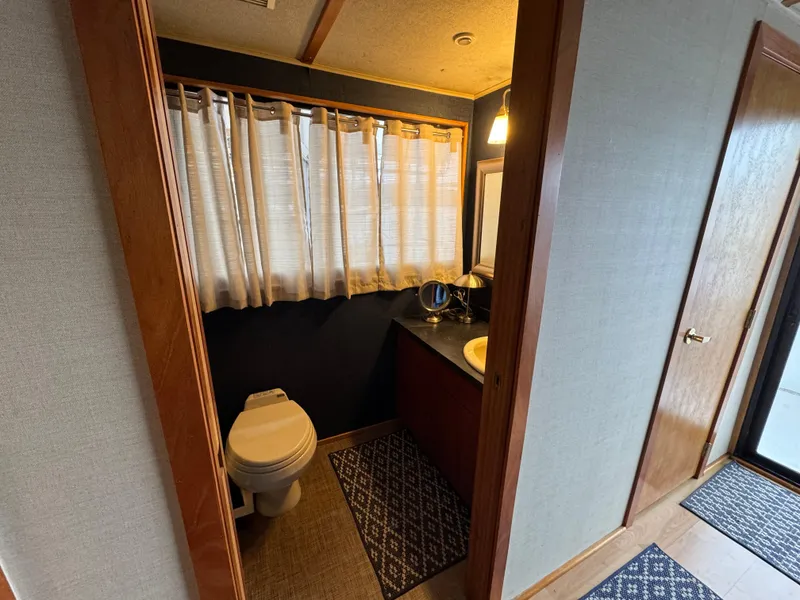 Slide: The Image of Bathroom interior of 1996 Skipperliner 560 Coastal Cruiser with toilet, sink, and window curtains. - 34