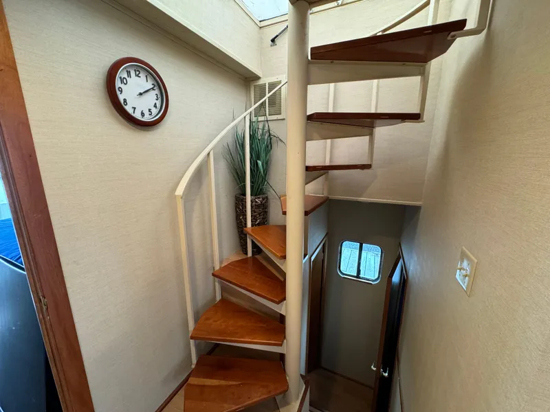 Slide: The Image of Spiral staircase inside 1996 Skipperliner 560 Coastal Cruiser with wall clock and potted plant. - 41