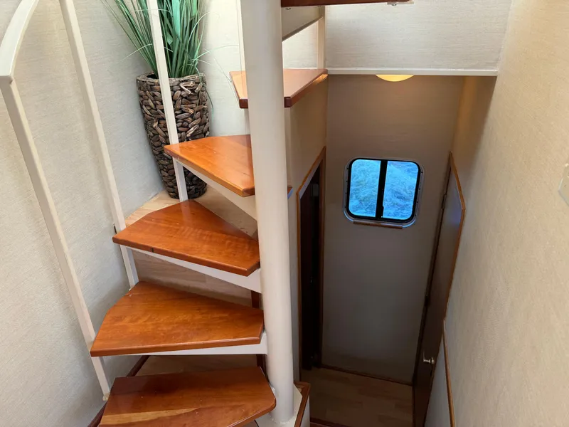 Slide: The Image of Spiral staircase inside 1996 Skipperliner 560 Coastal Cruiser with wooden steps and decorative plant. - 42