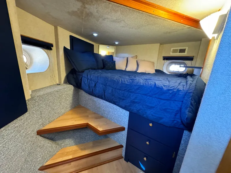 Slide: The Image of Cozy bedroom in 1996 Skipperliner 560 Coastal Cruiser with blue bedding and wooden steps. - 49