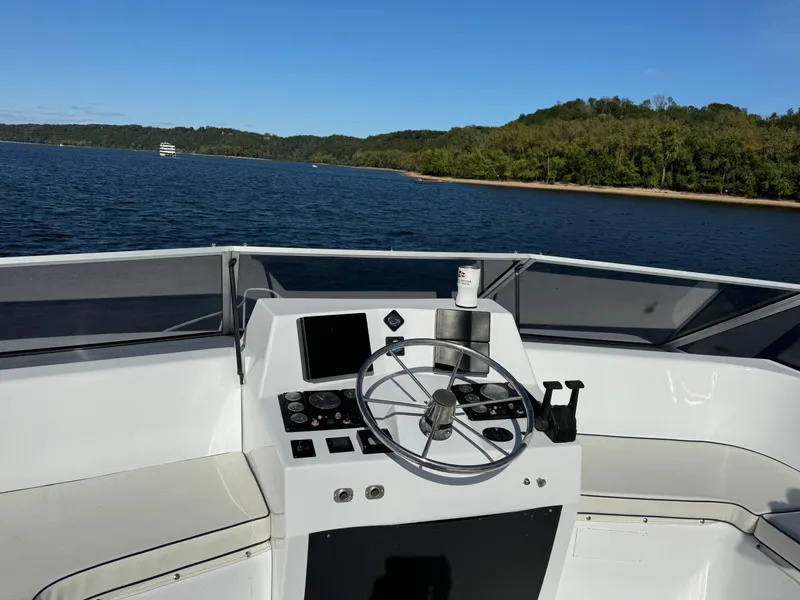 Slide: The Image of 1996 Skipperliner 560 Coastal Cruiser helm with scenic lake and forest backdrop. - 7