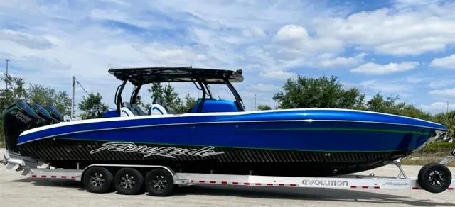 The Image of 2025 Renegade 38 Open boat in blue on a trailer, under a partly cloudy sky. - 1