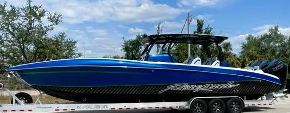 Slide: The Image of 2025 Renegade 38 Open boat on trailer, blue and black design, parked outdoors. - 3