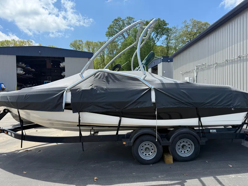 Slide: The Image of 2004 Rinker Captiva boat on trailer, covered, parked near industrial building. - 6