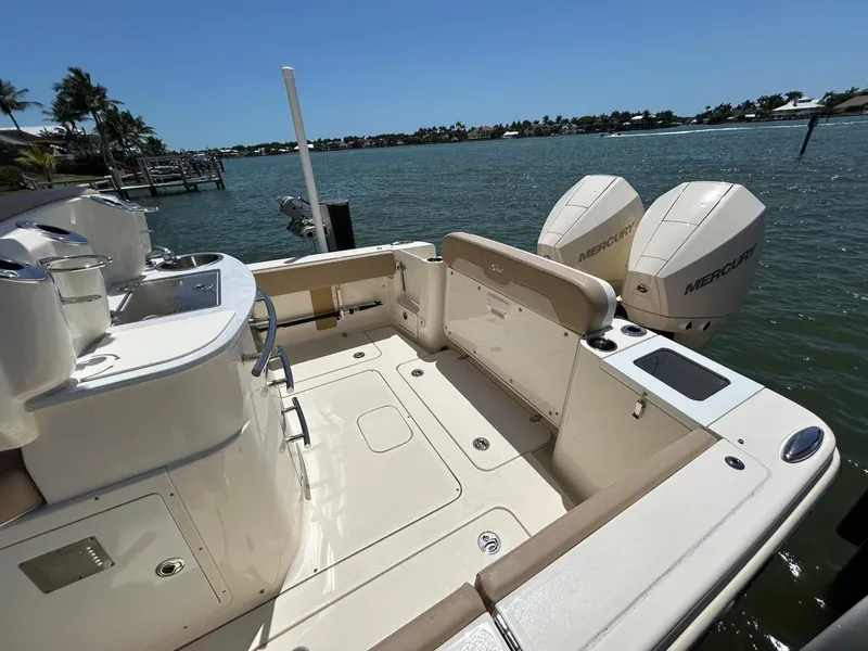 Slide: The Image of 2023 Scout 277 LXF boat with dual Mercury engines, docked by a scenic waterfront. - 10