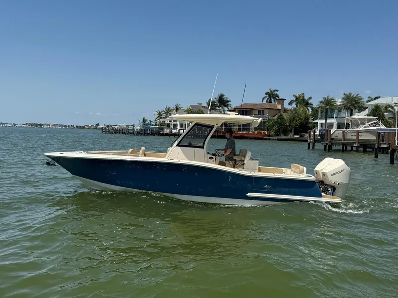 Slide: The Image of 2023 Scout 277 LXF boat cruising on a sunny day near waterfront homes. - 3