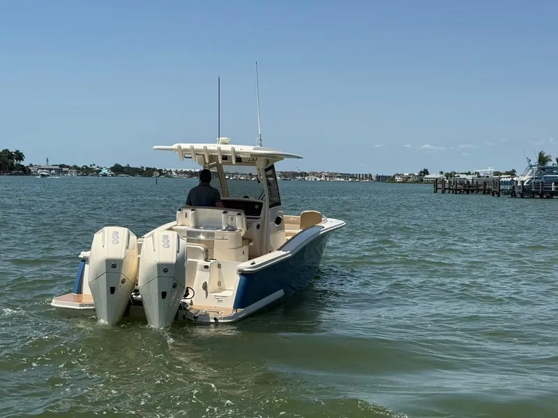 Slide: The Image of 2023 Scout 277 LXF boat cruising on a calm waterway with dual engines. - 5