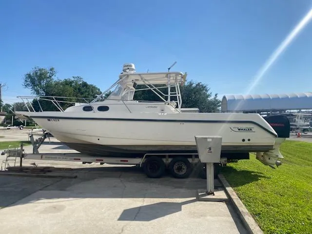 The Image of 2001 Boston Whaler 28 Conquest boat on trailer, parked outdoors under clear sky. - 0