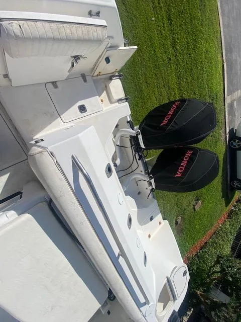 Slide: The Image of 2001 Boston Whaler 28 Conquest boat with Honda engines, docked on grass. - 30