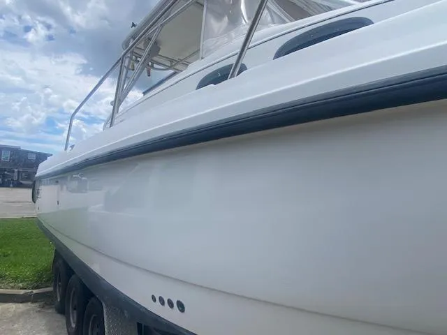 Slide: The Image of 2001 Boston Whaler 28 Conquest boat, side view, parked outdoors under cloudy sky. - 34