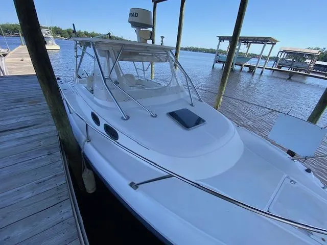 Slide: The Image of 2001 Boston Whaler 28 Conquest docked by a wooden pier on a sunny day. - 4