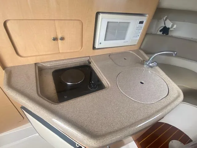 Slide: The Image of Compact kitchen area in a 2001 Boston Whaler 28 Conquest boat, featuring a stove and microwave. - 41