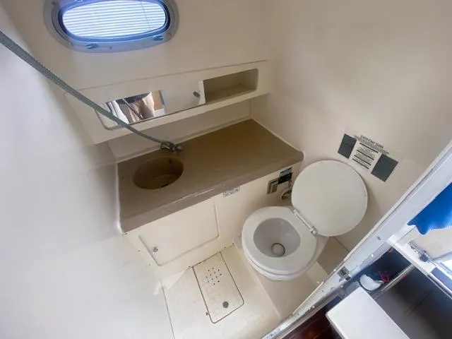 Slide: The Image of 2001 Boston Whaler 28 Conquest boat bathroom with sink, toilet, and storage shelves. - 42