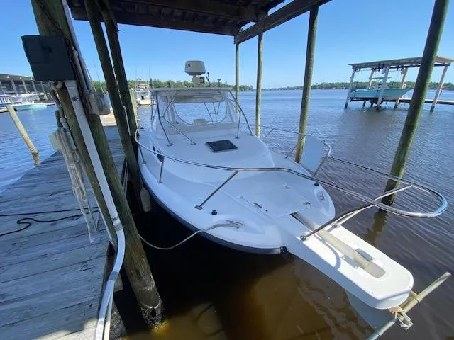 Slide: The Image of 2001 Boston Whaler 28 Conquest docked under a wooden shelter on a sunny day. - 6