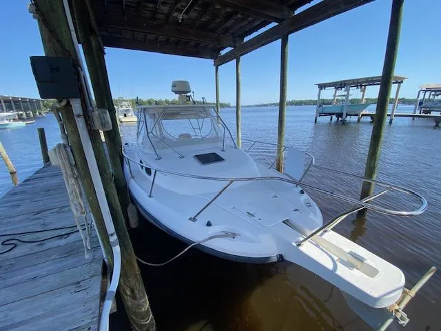 Slide: The Image of 2001 Boston Whaler 28 Conquest docked under a wooden shelter on calm waters. - 8