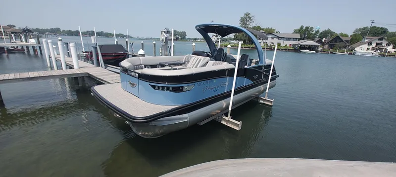 Slide: The Image of 2021 Bennington RX 25 RXFBA pontoon boat docked on a calm lake. - 0