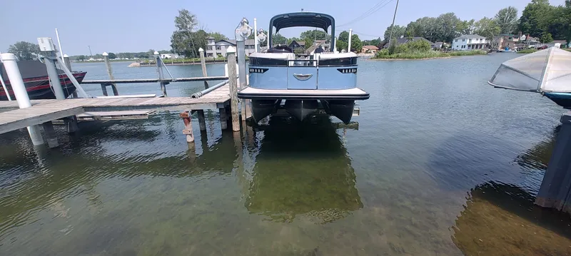 Slide: The Image of 2021 Bennington RX 25 RXFBA boat docked on a clear lake with scenic background. - 1