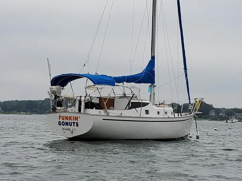 The Image of 1977 Bombay Express sailboat with blue canopy anchored on calm water. - 0