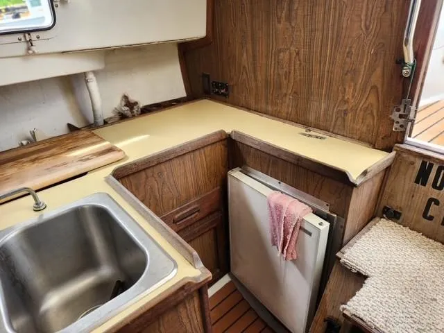 Slide: The Image of 1977 Bombay Express boat kitchen with wood cabinets, sink, and compact fridge. - 9