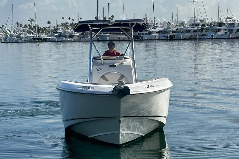 Slide: The Image of 2004 Boston Whaler 270 Outrage boat cruising in a marina with yachts in the background. - 10