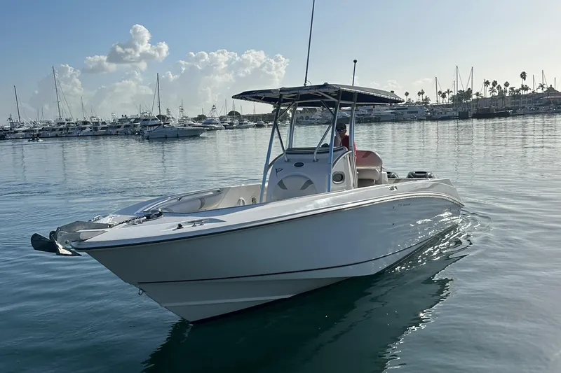 Slide: The Image of 2004 Boston Whaler 270 Outrage boat on calm water, marina in background. - 11