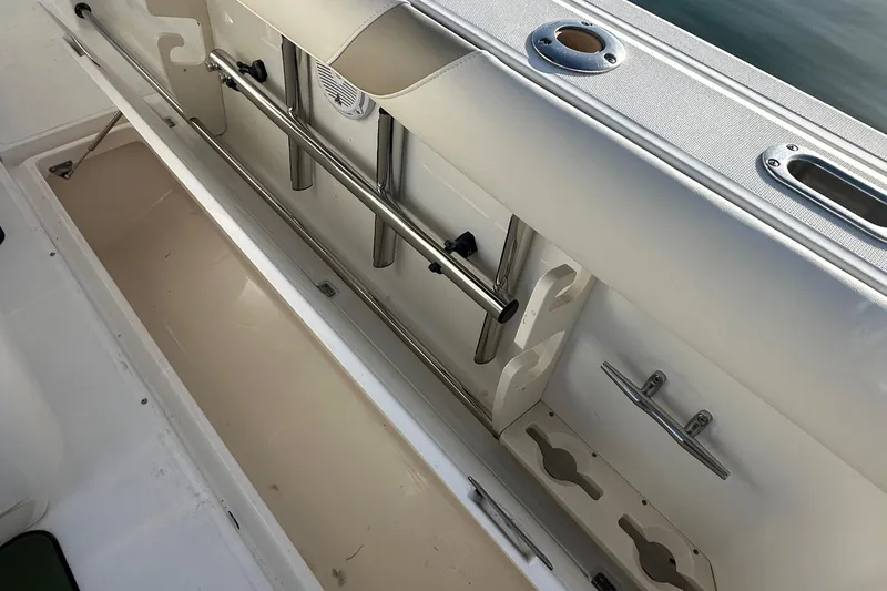 Slide: The Image of 2004 Boston Whaler 270 Outrage boat storage compartment with rod holders and cleats. - 24