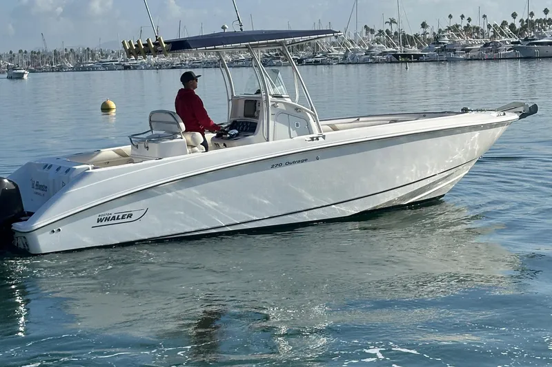 Slide: The Image of 2004 Boston Whaler 270 Outrage boat cruising on calm water with a person at the helm. - 7
