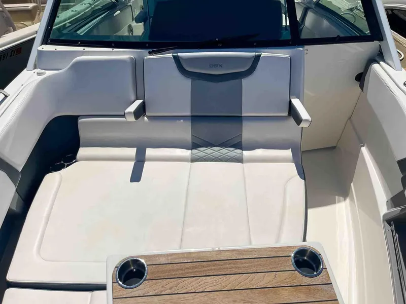 Slide: The Image of 2021 Chaparral 300 OSX boat interior with cushioned seating and wooden table. - 23