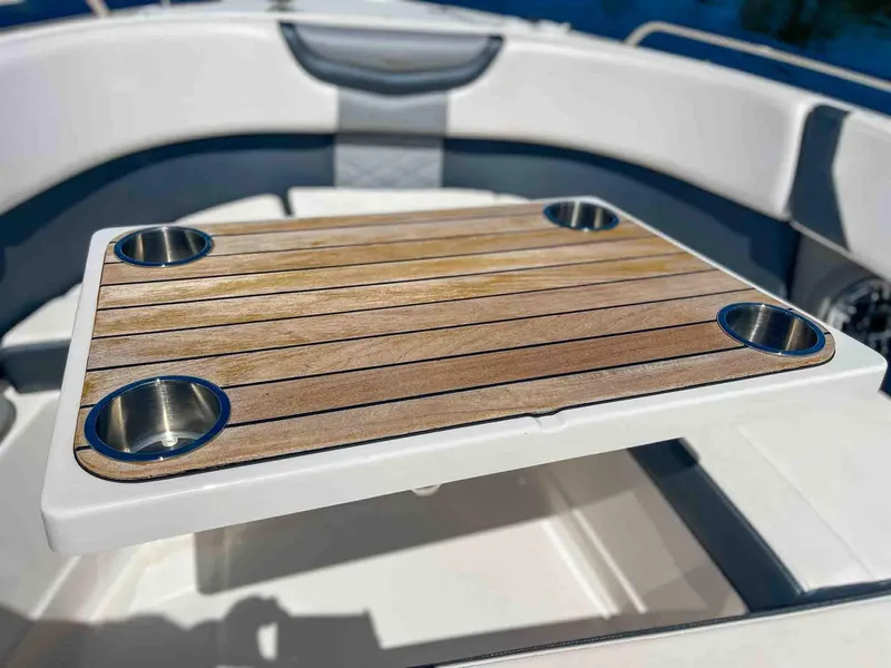 Slide: The Image of 2021 Chaparral 300 OSX boat interior with wooden table and cup holders. - 26