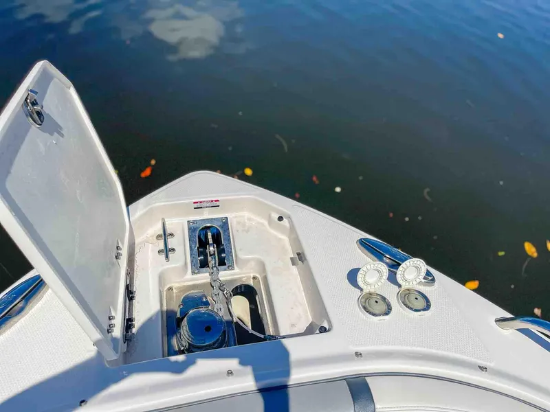 Slide: The Image of 2021 Chaparral 300 OSX boat anchor compartment open, showing chain and winch by water. - 27