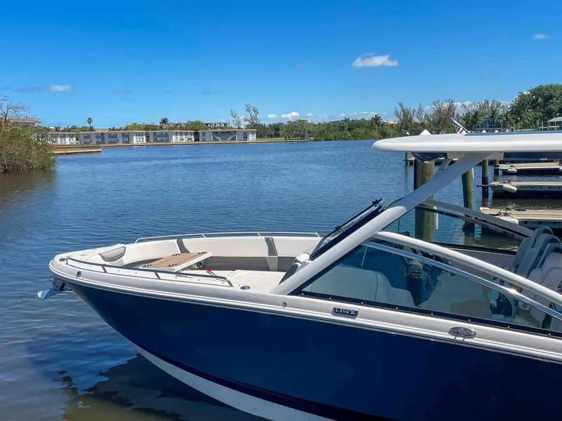 Slide: The Image of 2021 Chaparral 300 OSX boat docked on a serene lake under a clear blue sky. - 3