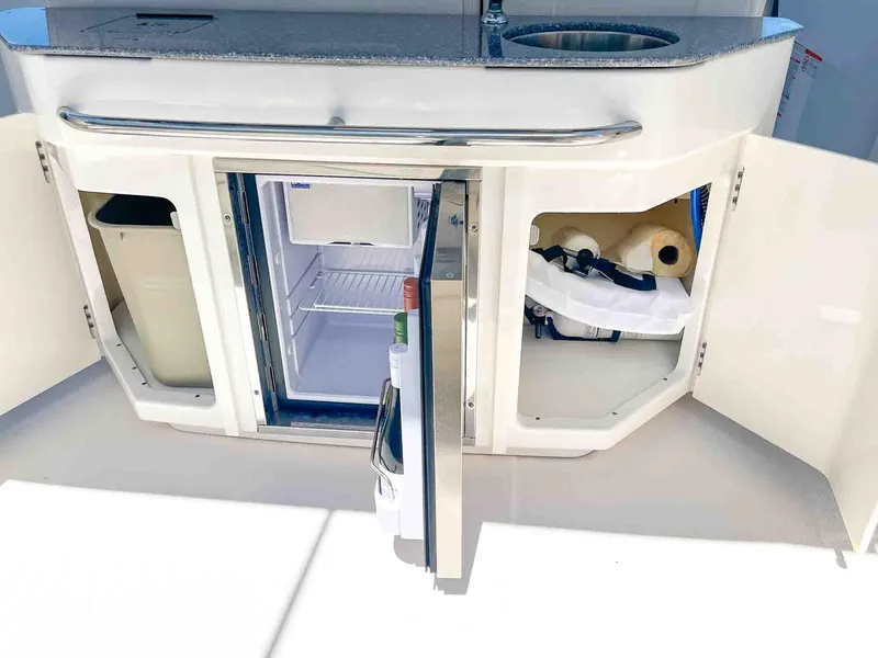 Slide: The Image of 2021 Chaparral 300 OSX boat kitchenette with open cabinets and mini fridge. - 32