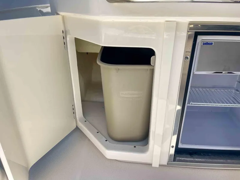 Slide: The Image of 2021 Chaparral 300 OSX boat interior with trash bin and mini fridge. - 34