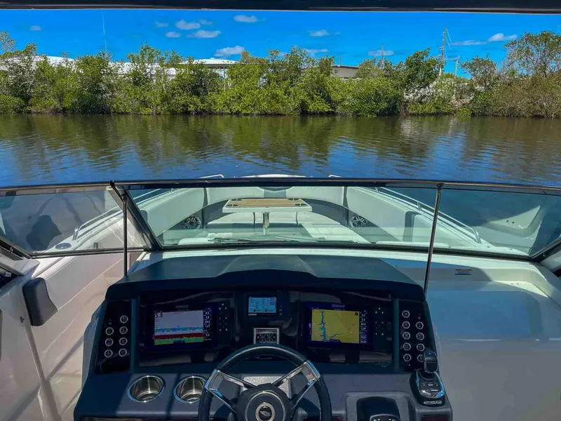 Slide: The Image of Cockpit view of 2021 Chaparral 300 OSX boat with navigation screens on a calm river. - 9