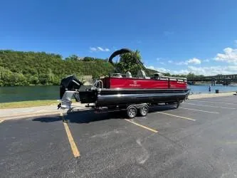 Slide: The Image of 2024 Regency 250 DL3 pontoon boat on trailer by a scenic lake. - 0