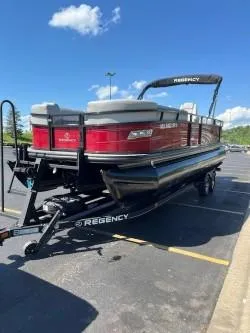 Slide: The Image of 2024 Regency 250 DL3 pontoon boat on trailer in parking lot, sunny day. - 2