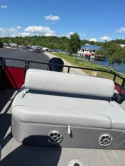 Slide: The Image of 2024 Regency 250 DL3 pontoon boat with gray seating, docked by a scenic lake. - 6