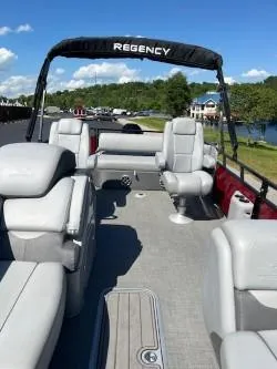 Slide: The Image of 2024 Regency 250 DL3 pontoon boat with spacious seating, gray upholstery, and scenic lake backdrop. - 9